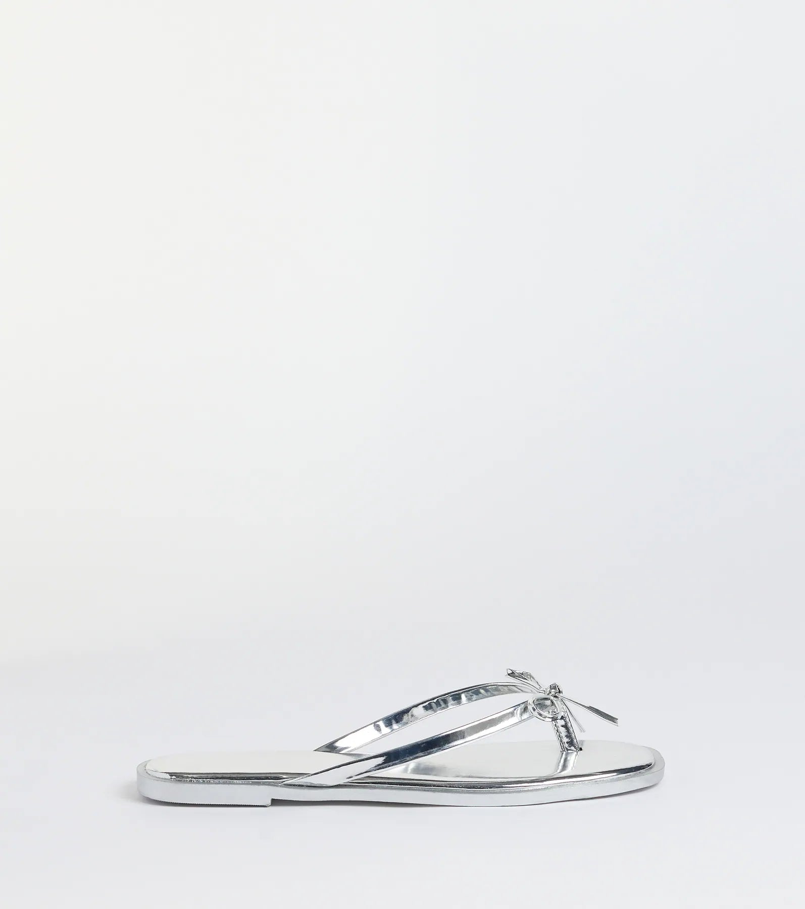 Elevate warm-weather looks with Dainty Looks Bow Thong Sandals in silver, a pair of trendy sandals bringing chic, modern flair to every step.